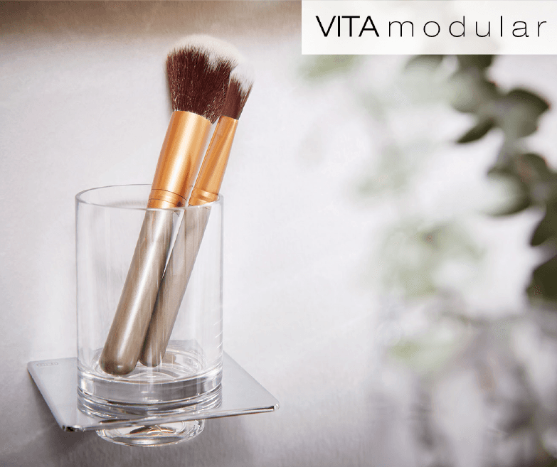 Accessoires für das Badezimmer: Glashalter an der Wand montiert, mit verchromten Unterteil. In dem Glasbehälter befinden sich zwei Kosmetikpinsel. Der Glasbehälter ist von der P&M Marke Vita Modular.